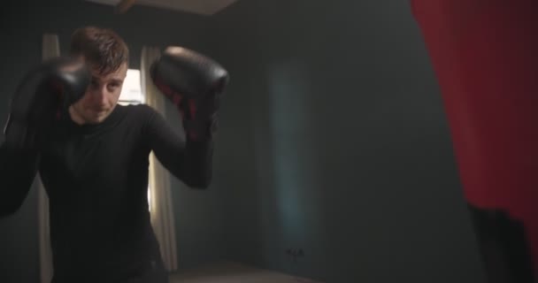 Молодий атлетичний чоловік влучає в боксерську сумку. Боксер практикує удари в кільці. Спортсмен завдає удару мішком для ударів. 4k відео
 - Кадри, відео