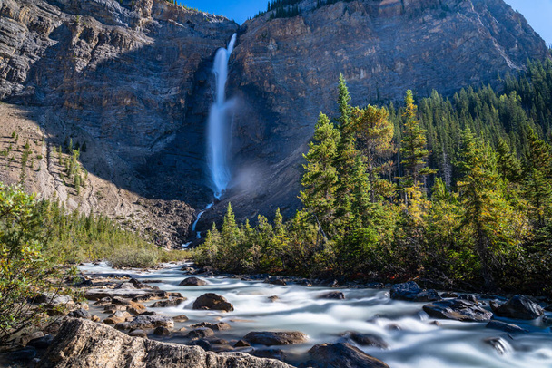 Wodospad Takakkaw i rzeka Yoho w słoneczny letni dzień. Krajobraz przyrodniczy w Parku Narodowym Yoho, Canadian Rockies, Kolumbia Brytyjska, Kanada. - Zdjęcie, obraz