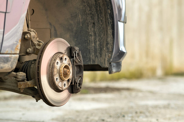 Gros plan du disque de freinage du véhicule avec étrier de frein pour réparation en cours de remplacement des pneus neufs. Réparation des freins de voiture dans le garage. - Photo, image