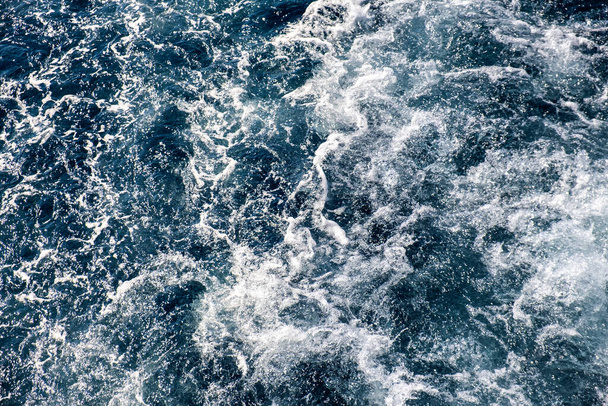 Luftaufnahme der Meeresoberfläche von oben nach unten. Weiße Schaumwellen als natürlicher Hintergrund. - Foto, Bild