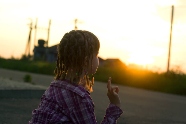 Mladý pěkný dítě dívka s legrační copánky trénink jóga cvičení sám venku na zamlžené venkovské pozadí za úsvitu nebo západu slunce. - Fotografie, Obrázek