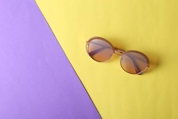 Elegantes gafas de sol redondas de moda sobre fondo de papel azul rosado. Vista superior. Minimalismo - Foto, Imagen