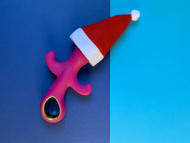 Sexspielzeug und Neujahr. Pinkfarbener Vibrator auf blauem Hintergrund. Nützlich für Erwachsene, Sexshop - Foto, Bild