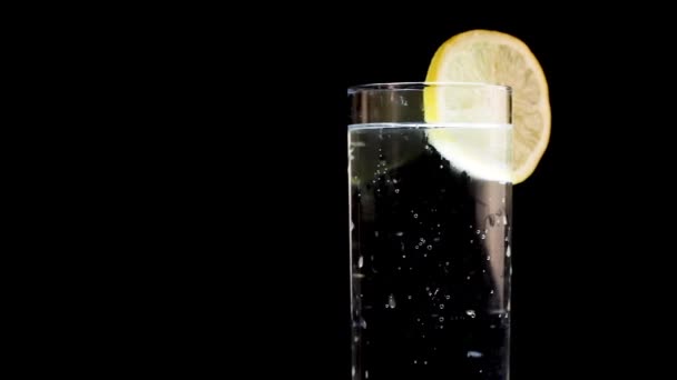 Αφρώδες νερό με σφήνα λεμονιού Περιστροφή σε απομονωμένο μαύρο φόντο - Πλάνα, βίντεο