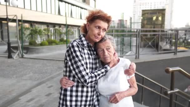 Kaukasische ältere Frauen umarmen Mutter und Tochter in der Stadt mit Liebe, Fürsorge, Hilfe, Unterstützung und Sympathie. Aufrichtige Familie verschiedener Altersgenerationen, die miteinander reden und Spaß haben - Filmmaterial, Video