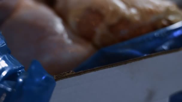 Makró kilátás egy dobozra tele fagyasztott csirkelábakkal. Jéggel borított, fagyasztott nyers csirkehús. 4k videó - Felvétel, videó
