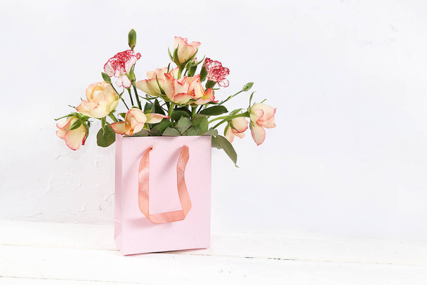 Roses with a gift on a pink table, abstract spring floral background. Creative modern bouquet, minimal holiday concept. Greeting card for Women's Day or Mother's Day, happy birthday, wedding, gift for loved ones, place for text, banner for screen, - Fotoğraf, Görsel