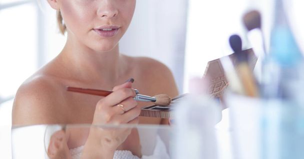 A picture of a young woman applying face powder in the bathroom - Photo, image