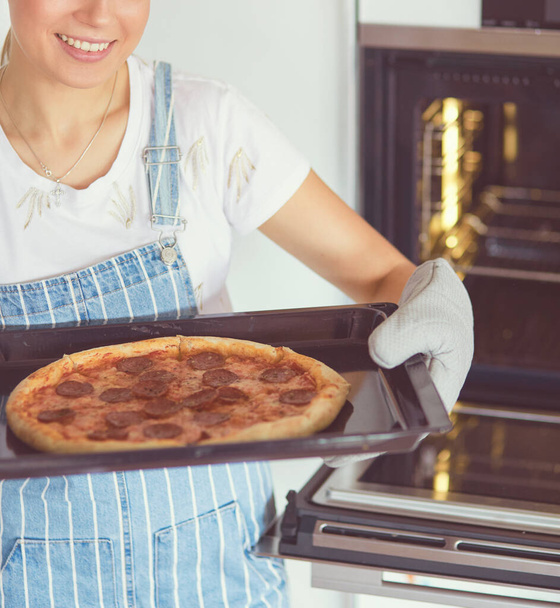 Happy young woman cooking pizza at home - Photo, image