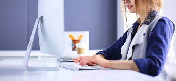 Young confident businesswoman working at office desk and typing with a laptop - Fotoğraf, Görsel