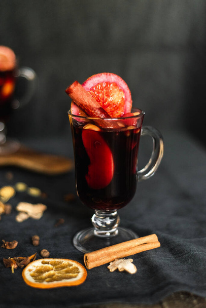 Christmas mulled red wine with aromatic spices and citrus fruits on a table, close-up. Traditional hot drink at Christmas time - Foto, Bild