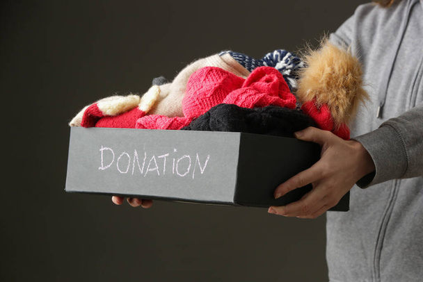 Dobrovolnice ženy držící dárcovskou krabici s teplým vlněným zimním oblečením, klobouky, ponožky, rukavice... - Fotografie, Obrázek