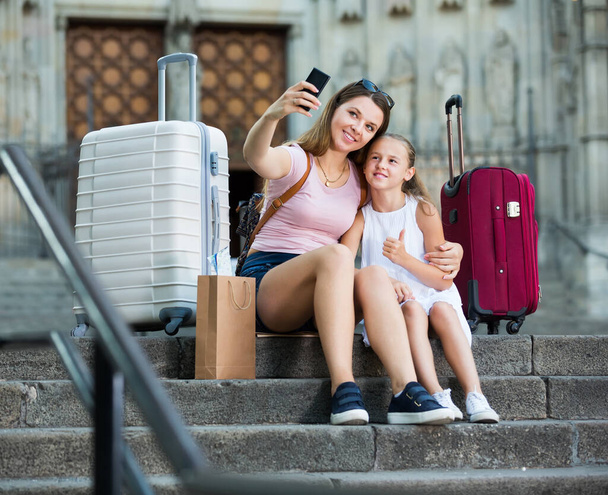 sonriente madre con hija viajeros y tomando selfie - Foto, Imagen