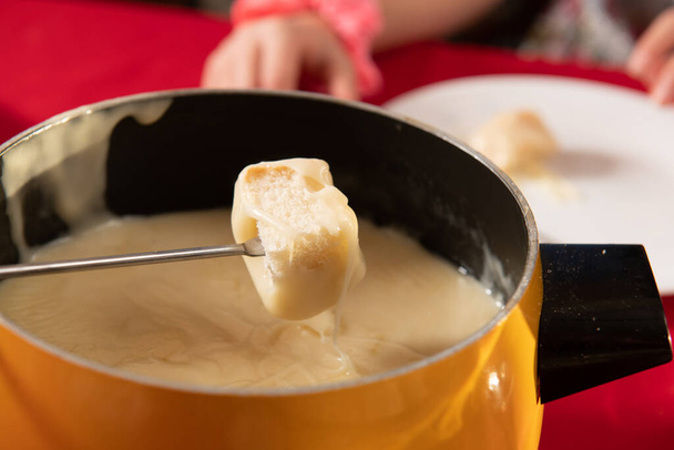Bread being dipped in Swiss Cheese for fondue dinner - Photo, Image