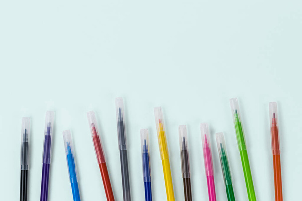 Egy sor színes jelölők borított sapkák egy könnyű háttér. Univerzális markerek iskola, iroda, és hobbi. - Fotó, kép