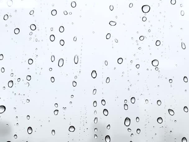 Regenwassertropfen fallen auf das Fensterglas. Weißwassertropfen auf blaues Glas. Regentropfen auf Fensterscheiben, Wassertropfen, die auf die Glasoberfläche fallen. Wassertropfen fallen. Drop. Regen. - Filmmaterial, Video