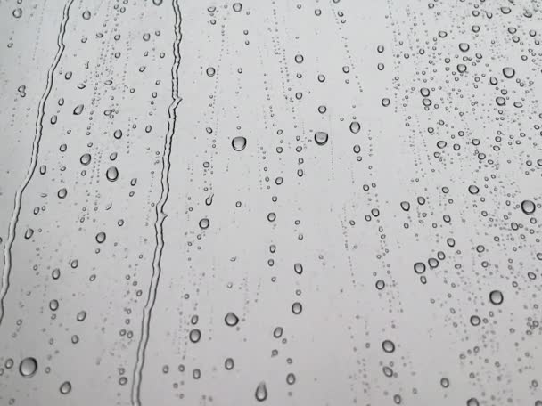 Esővíz cseppek esnek az ablaküvegre. Fehér víz cseppek a kék üvegre. Eső cseppek ablak .vízcseppek alá üveg felületen. Vízcseppek hullanak. Dobd el! Esés. - Felvétel, videó