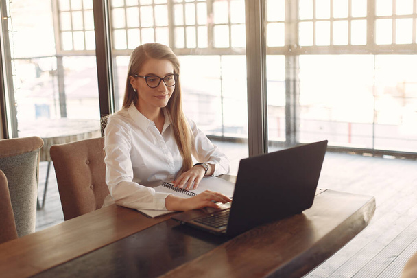Businesswoman sitting at the table with a laptop - Foto, Imagen