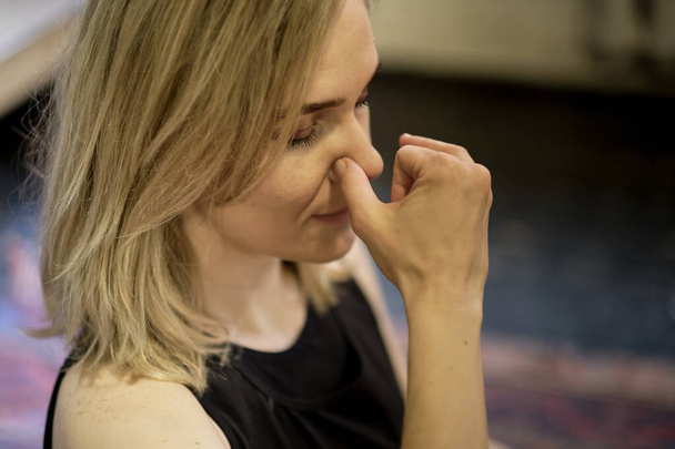鼻孔の変化で呼吸する。中世の女性が呼吸法ヨガ瞑想プラナヤマをしています。近くで指が鼻を閉じて呼吸するナディ・ショダナ - 写真・画像