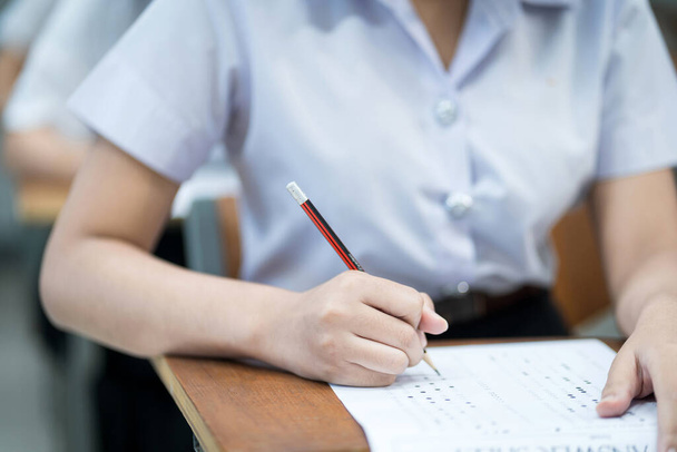 Nahaufnahme der jungen Universitätsstudenten konzentrieren sich auf die Prüfung im Hörsaal. Schülerin schreibt Prüfungsaufgaben im Klassenzimmer. - Foto, Bild