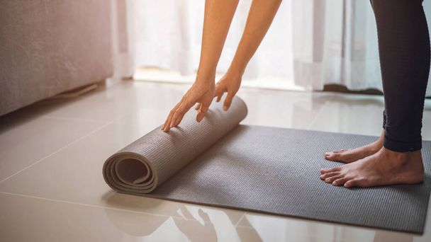 Woman rolling yoga mat after  yoga class. - Photo, Image