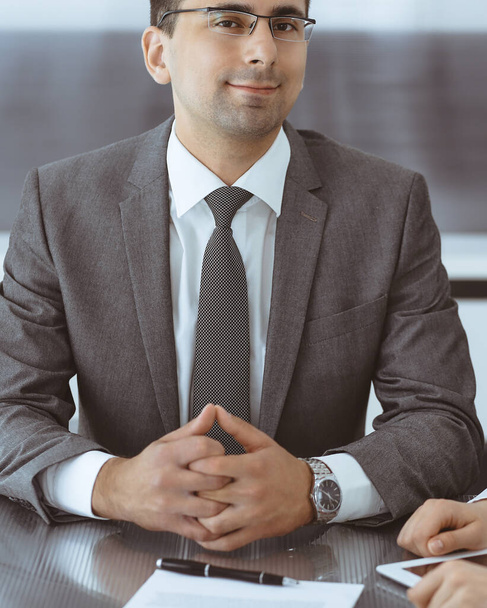 Businessman headshot at meeting in modern office. Entrepreneur sitting at the table with colleagues. Teamwork and partnership concept. Grey blazer suits to happy smiling manager - Photo, Image