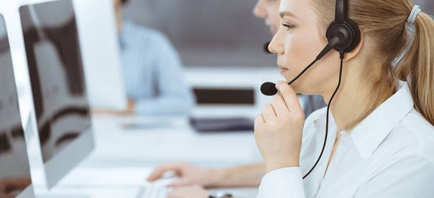 Call center. Group of casual dressed operators at work. Blond business woman in headset at customer service office. Telesales in business - Foto, Imagem