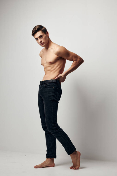 A man in jeans with a naked torso in full growth In a bright room - Photo, Image