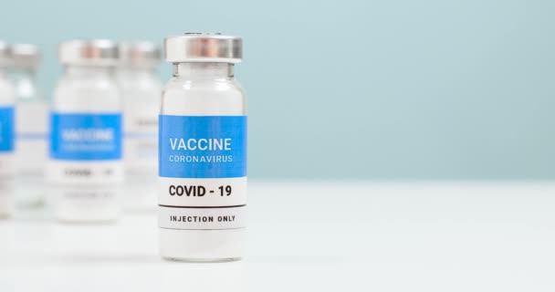 Короновирус, вакцинация населения ковидом-19. Стекло и шприц из бутылки вакцины SARS-CoV-2 на белом лабораторном столе с копирайтом. Здравоохранение концепция лечения. 4k - Кадры, видео