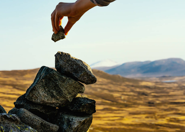 Hand het plaatsen van een rots op de top van een cairn op de top van een berg. Sluit maar af. . Hoge kwaliteit foto - Foto, afbeelding