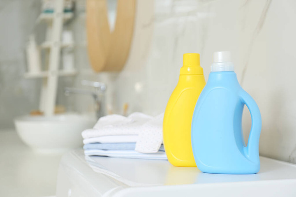 Bottles of detergent and children's clothes on countertop in bathroom. Space for text - Fotó, kép