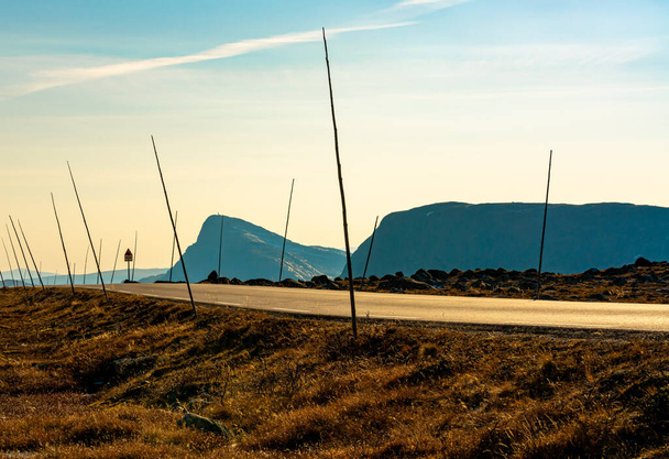 Lunga strada in montagna con segnaletica stradale bastoni pronti per l'inverno, sul lato è il monte Bitihorn. Profondità di campo ridotta. . Foto di alta qualità - Foto, immagini