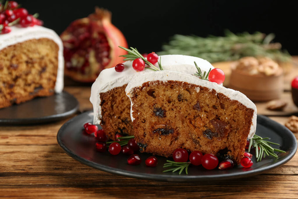 Traditional classic Christmas cake decorated with cranberries, pomegranate seeds and rosemary on wooden table - Foto, Bild