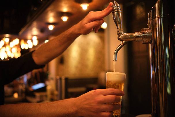Barman vertiendo cerveza en un vaso de un grifo de cerveza. - Foto, Imagen