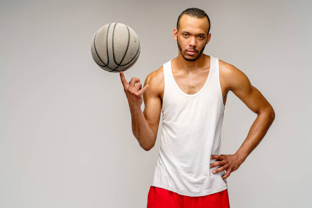 Muscular african american sportsman playing basketball over light grey background - Photo, image