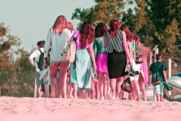 turyści z tyłu spacer wzdłuż plaży boso w słońcu w różowym, - Zdjęcie, obraz