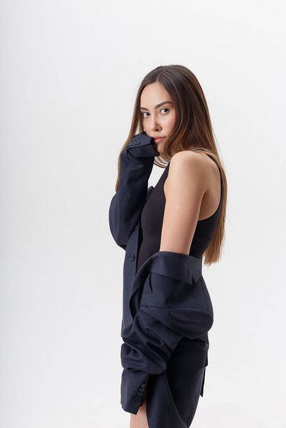jong aantrekkelijk aziatische vrouw in zwart bodysuit en blauw pak geïsoleerd op wit - Foto, afbeelding