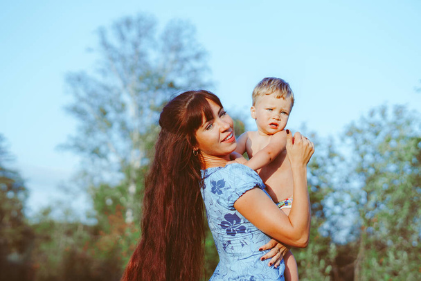 matka drží v náručí dítě, které stojí u řeky - Fotografie, Obrázek