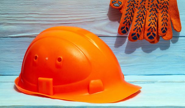 Construcción guantes de trabajo casco naranja contra el fondo de las tablas azules - Foto, Imagen