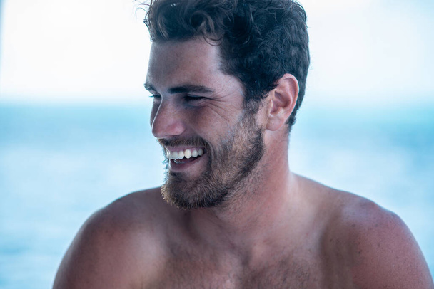 Portrait of handsome man with white teeth smile, shirtless surfer and blue ocean on background - Foto, Imagen