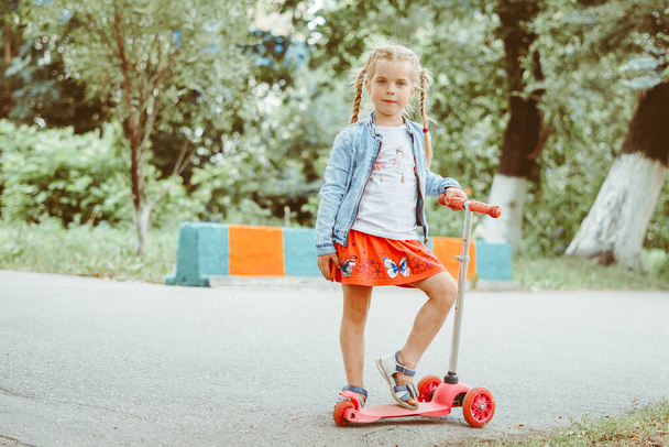 Маленька дівчинка катається в парку на скутері
 - Фото, зображення