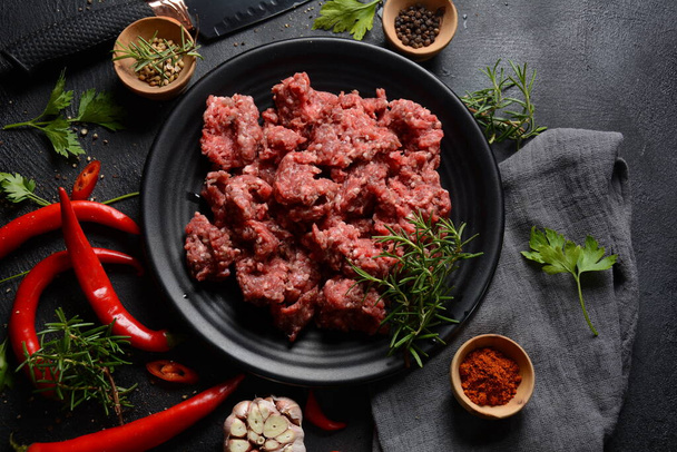 Minced beef. Ground meat with ingredients for cooking on black background - Foto, imagen