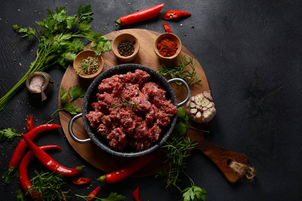 Minced beef. Ground meat with ingredients for cooking on black background - Foto, afbeelding
