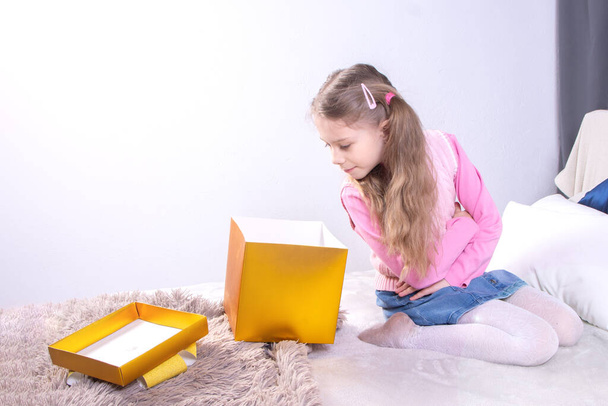 Söpö syntymäpäivä tyttö avaa laatikoita lahjoja, kun istuu sängyssä kotona. Käsite onnellinen lahja - Valokuva, kuva
