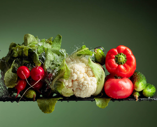 水のスプラッシュと様々な生野菜。緑の背景にカリフラワー、トマト、キュウリ、大根、パプリカ. - 写真・画像