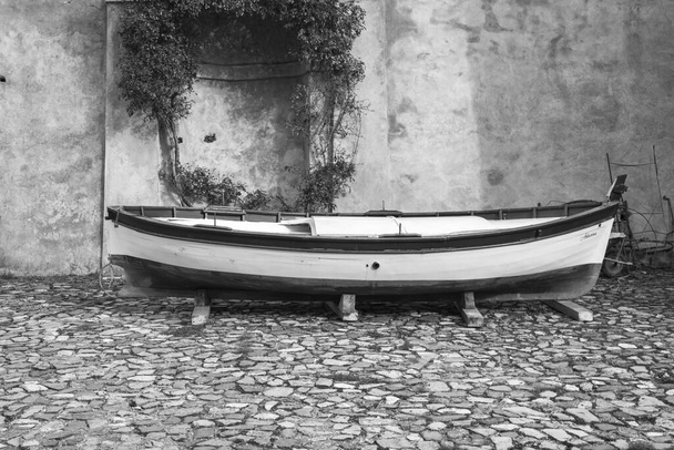 Antik Borgo Adorno şatosunun arka bahçesinde (Scrivia Valley, Piedmont, Kuzey İtalya) Piedmont ve Liguria bölgeleri arasındaki sınırda bulunan antik balıkçı teknesi. Siyah beyaz fotoğraf. - Fotoğraf, Görsel