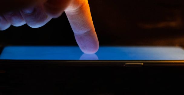 Concepto tecnológico con un dedo tocando la pantalla de un gadget. - Foto, imagen
