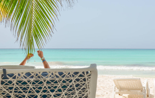Un jeune homme leva les mains en l'air alors qu'il était assis sur une chaise sur la plage, Dominicana. - Photo, image
