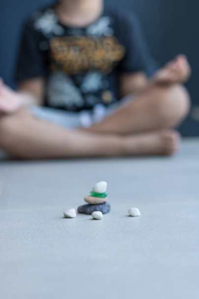 Stapeln von Kieselsteinen, während das Kind im Hintergrund Yoga praktiziert. Kopierraum. - Foto, Bild