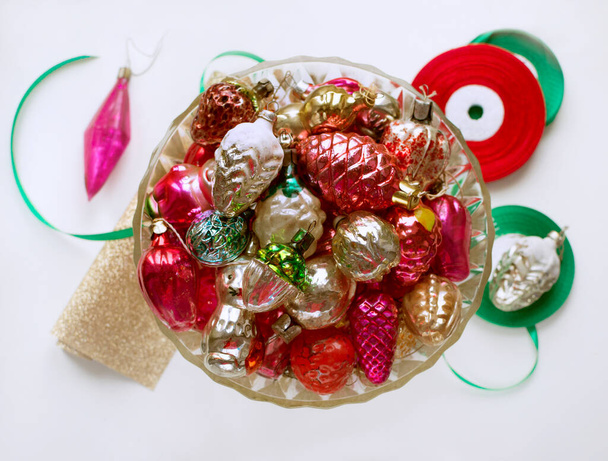 Ano Novo e Natal velho estilo retro ornamentos de vidro na tigela e suprimentos de decoração verde vermelho, foco seletivo, vista superior, fundo branco - Foto, Imagem